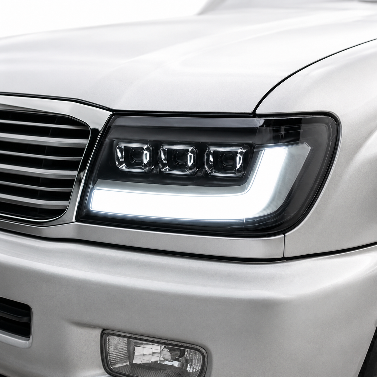 LandCruiser 100 Series bi-LED headlight installed — driver side close-up showing projector lens and DRL