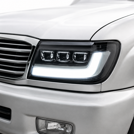 LandCruiser 100 Series bi-LED headlight installed — driver side close-up showing projector lens and DRL